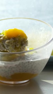 Kadınlar beyaz arka planda sağlıklı bir tatlı hazırlamak için şeffaf bir bardağa yoğun yoğurt ve chia tohumu koyarlar. Yüksek kalite 4k görüntü