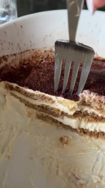 Dikey video tiramisu, beyaz bir tabak İtalyan kahvesi ve kremalı Mascarpone tatlısı çatalıyla yenmiş kakaolu tatlı sofistike bir gelenek serpiştirilmiş. Yüksek kalite 4k görüntü