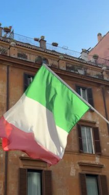 Ulusal İtalya Günü. Bir İtalyan bayrağını binanın balkonunda süslenmiş detaylar ve güneş ışığıyla yakalanmış ahşap panjurlarla yakın plan görüntüsü. Yüksek kalite 4k görüntü