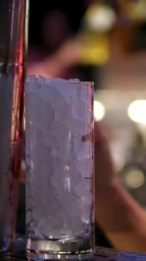 Barmen barın tezgahında kokteyl hazırlamak için şişeden cigger 'a likör dolduruyor. Arka planda hassasiyet ve canlı yeşil neon ışıklara odaklanıyor. Yüksek kalite 4k görüntü