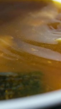 Bir kase ev yapımı tavuk çorbası haşlanmış yumurta, sebze ve taze otlar. Bir kaşık kasenin içinde duruyor. Kaynamış yumurtayla birlikte bambu hasırında servis edilen doyurucu ve sağlıklı bir yemek. Diyet tavuk çorbası..