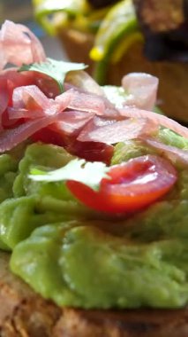 Şef taze yeşillikler, mantarlar ve baharatlarla süslenmiş lezzetli bir avokado tostu sunarak sağlıklı ve görsel olarak çekici içerikleri vurguluyor. Yüksek kalite 4k görüntü