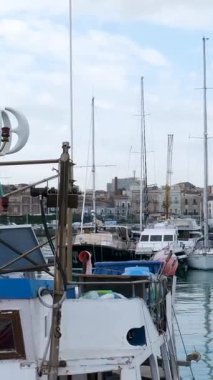 Catania Sicilya limanına yanaşmış tekne ve yatların huzurlu manzarası berrak mavi su güneş ışığı ve rahat Akdeniz havasıyla. Catania Sicilya İtalya 10.05.2025