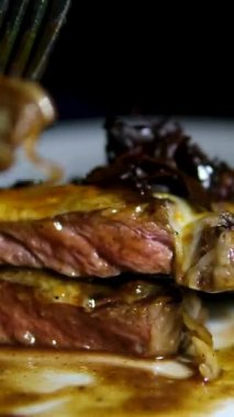 Bir çatal tarafından alınan yumuşak bifteğin yakın çekimi, sulu, mükemmel pişirilmiş iç mekanı ortaya çıkarıyor. Zengin dokusu ve cızırtılı yüzeysel lezzeti. Aşçılık videoları. Yüksek kalite