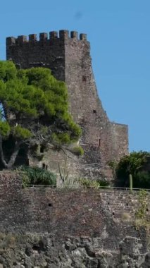 Aci Castello Norman kalesi, Catania Sicilya yakınlarındaki İyon Denizi 'ne bakan siyah lav uçurumunda duruyor. İtalya tarihi ortaçağ kalesi ve manzaralı Akdeniz kıyıları..