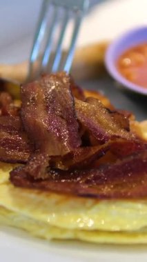 Kabarık bir omleti tabakta kesmek. Jambonlu omlet, domates.