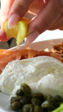 Mozzarella, bezelye, fasulye, ıspanak, kızarmış ekmek ve böğürtlen tabakları. Kadınların elleri kahvaltıyı hazırlıyor. Hafif tuzlu somona limon sık. Yüksek kalite 4k