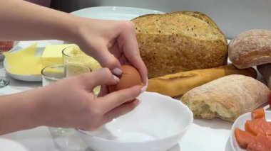 Kadın yumurta kırıyor ve gri desenli masada sarısını beyazdan ayırıyor. Yakın plan. Beyazları ve sarıları ayır