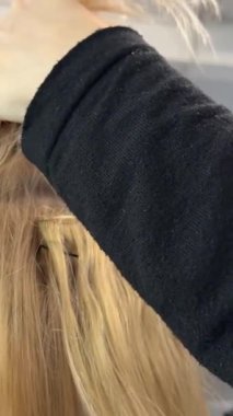 Sahte saç telleri kuaförde oturmuş aynadaki yansımasına, kendine bakmasına bakarak saçını yetenekli kuaföre yaptırıyor. Doğal Avrupa saç telleri