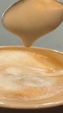 İçi sıcak kahve dolu, köpüklü, kalın bir kahve fincanı ve içinde kahve aşıkları için mükemmel bir kaşık olan bir kaşık. Yüksek kalite 4k görüntü