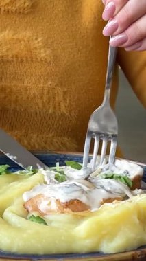 Restoranda patates püresi ve kremalı soslu kafede et yiyen bir kadın. Sarı ceketli bir öğle yemeğinde. Yüksek kalite 4k görüntü