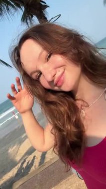 Yaz, saçları çiçekli siyah mayo giymiş bir kadın kumlu sahilde oturur, arka planda deniz ile dinlenir, maldivlerde huzurlu bir an, yaz tatili, tropikal bir tatil. .