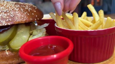 Bir kafede Fast Food kızartması ve et burger yiyen bir kız. Ketçap kızartması.