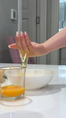 Mutfak hazırlıkları sırasında yumurta sarısını cam bardakta saklarken paslanmaz çelik kaseye dikkatlice yumurta beyazı dökerek yumurtayı ayıran şefe yaklaş. Beyazları ve sarıları elle dök