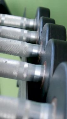 Odaklanmış bir sporcunun, spor salonundaki dambılları seçerken, spor salonundaki kendini adamışlık ve dayanıklılığı gösteren yakın çekim görüntüleri. Odaklanmış Atletizm Çalışmaya Hazırlanıyor .