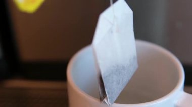 Sıcak su çaydanlıktan çay poşetiyle beyaz bir çay bardağına dökülüyor. Yüksek kalite 4k görüntü