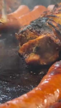 Sulu sosisler ızgarada cayır cayır yanıyor. Kara barbekü atmosferinde duman ve alevler var. Yüksek kalite 4k görüntü