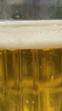 Sıcak bir birahanede ya da bira fabrikasında cam bardakta köpüklü bira bardağına yakın çekim. Yüksek kalite 4k görüntü