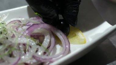 Beyaz bir tabakta hafif tuzlanmış ringa balığı, koyu zeytinlerle süslenmiş ve limonla marine edilmiş soğan. Yüksek kalite 4k görüntü