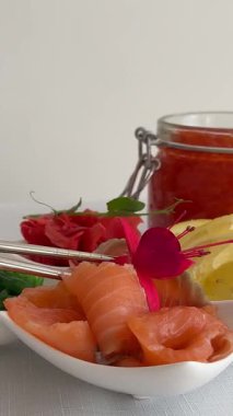 Yenilebilir çiçekli garnitür, sashimi, tabakta limonlu hafif tuzlu kırmızı balık, bir kavanoz kırmızı havyar. Yüksek kalite 4k görüntü