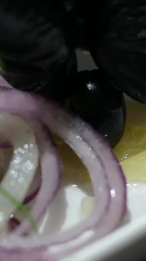 Beyaz bir tabakta hafif tuzlanmış ringa balığı, koyu zeytinlerle süslenmiş ve limonla marine edilmiş soğan. Yüksek kalite 4k görüntü