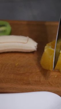 Tahta kesme tahtasındaki bıçakla taze muzu doğramaya yakın çekim. Yüksek kalite 4k görüntü