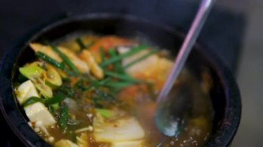 Fesleğen yapraklarıyla süslenmiş deniz ürünleri ve masada beyaz tabakta kiraz domatesli domates çorbası. Midye, kabuk ve tofu peynirli deniz ürünleri çorbası.