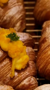 Mangolu kruvasan ve üzeri mango kremalı pudra şekerli hamur tatlısı, dokusunu ve parlak malzemesini vurgulayan yumuşak kamera hareketi, tatlı yemek görüntüleri. Yüksek kalite 4k görüntü