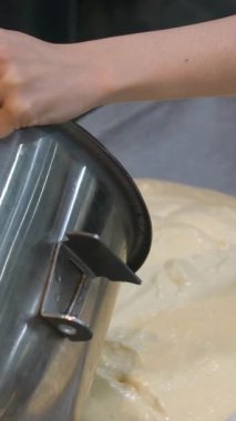Bir kadın karıştırma kabından kağıt kaplı bir tepsiye sünger kek hamuru dökerek ev mutfağında pişirmeye hazırlanıyor. Yüksek kalite 4k görüntü