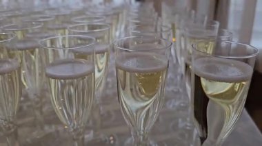 Bardağın kenarından şampanya dökülen bir parti için lüks yemekler. Lüks parti kavramı. Piramit ya da kule şeklinde dizilmiş şampanya kadehlerinin dekoratif düzenlemesi