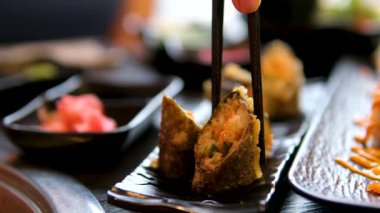 Lokantada kadın eli, lezzetli suşi rulosu ve çubukla yakın plan yemek yiyor. Hanımefendi ağır çekimde Asya yemeklerini seviyor. Lüks bir yaşam tarzı. Yüksek kalite 4k görüntü