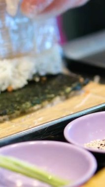 Şef eller suşi rulosu hazırlıyor, krem peynir sıkıyor. Yüksek kalite 4k görüntü