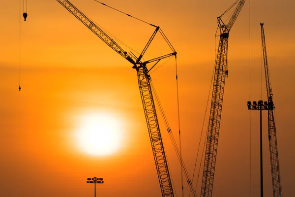 Tower crane on a construction site at sunset, Industrial construction cranes in silhouettes