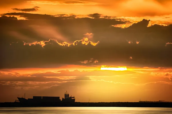 stock image Cargo ship floats on the ocean at sunset time, Industry Container cargo ship at coast in sunset sky, Transportation, Shipping, Logistics, Silhouette of Cargo ship in sunset.