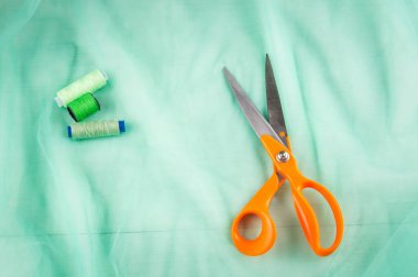 Makas terzi ve inç, santimetre bant ve yeşil tül kumaştan yapılmış yeşil iplikler. Terzi malzemeleri. Dikiş araçları.