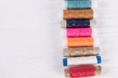 Beyaz ahşap arka planda çeşitli dikiş iplikleri