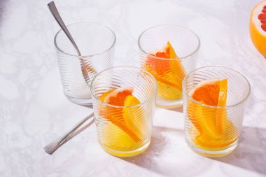 Portakallı, limonlu ve greyfurtlu limonata. Beyaz masada bir bardak limonata.