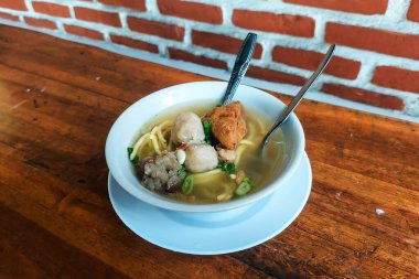 Köfteler, tahta bir masada kaşıklar ve çatallar.