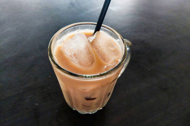 Büyük buz küpleri ve siyah pipetle bir bardak buzlu çikolatalı süt.