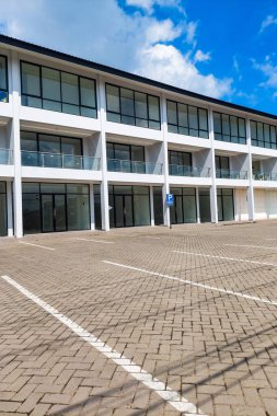 Lüks bir lojman manzarası, mavi gökyüzü arka planlı geniş bir park yeri.