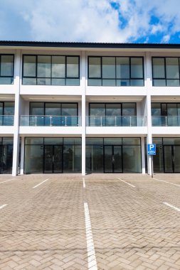 Lüks bir lojman manzarası, mavi gökyüzü arka planlı geniş bir park yeri.