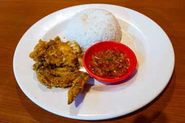 Pirinç, tavuk ve biber sosu ahşap bir masada beyaz bir tabakta.