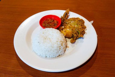 Pirinç, tavuk ve biber sosu ahşap bir masada beyaz bir tabakta.