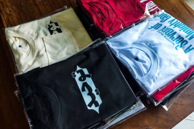 Makassar, Endonezya, 23 Ocak 2025, ahşap bir masaya paketlenmiş renkli tişörtler.