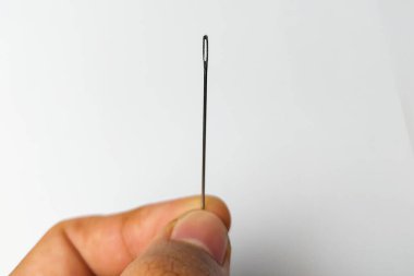 Dikiş iğnesi beyaz arka planda tutuluyor.