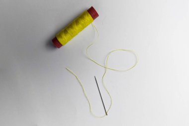 Beyaz arkaplanda sarı iplik ve iğne kullanılmış