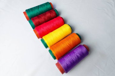 Beyaz arkaplanda sıralanmış renkli iplikler