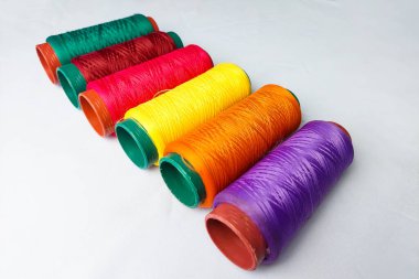 Beyaz arkaplanda sıralanmış renkli iplikler