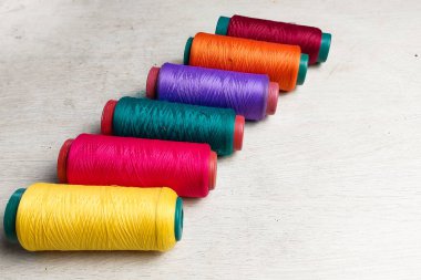 Beyaz arkaplanda sıralanmış renkli iplikler