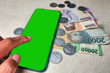 Banknotlar, madeni paralar ve cep telefonu yeşil ekranı elle kaydırılıyor